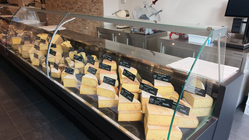 Vitrine de fromages à pâte dure à la coupe, boutique La Dent du Chat Châtelain