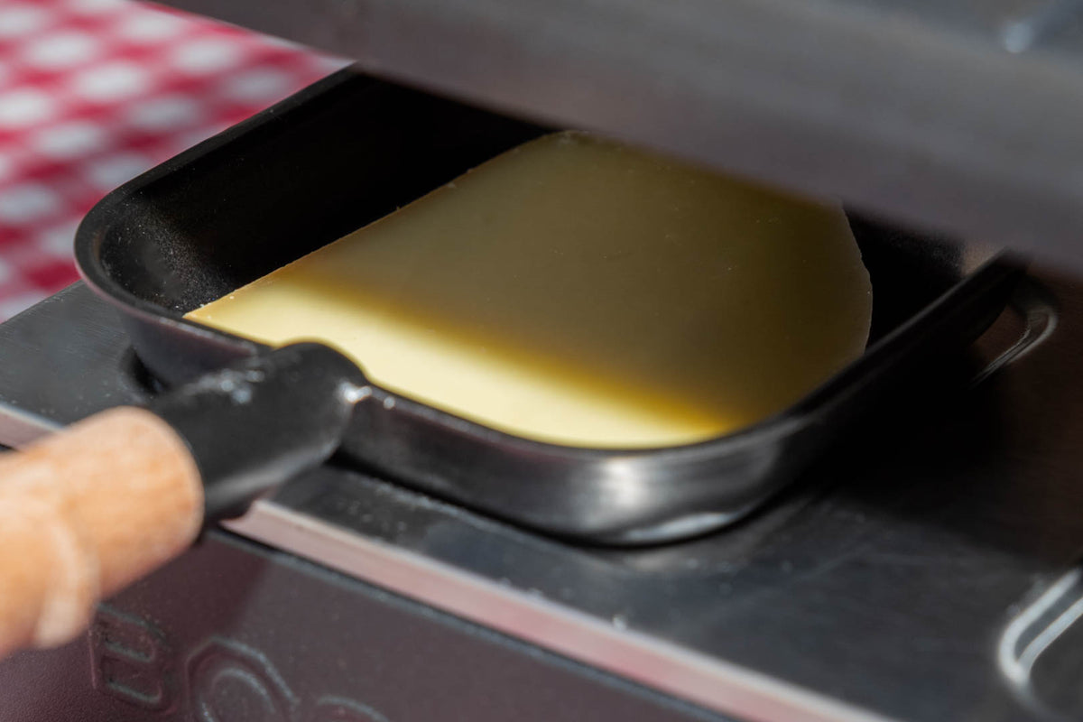 Raclette suisse de montagne, tranche qui fond sous l'appareil à raclette