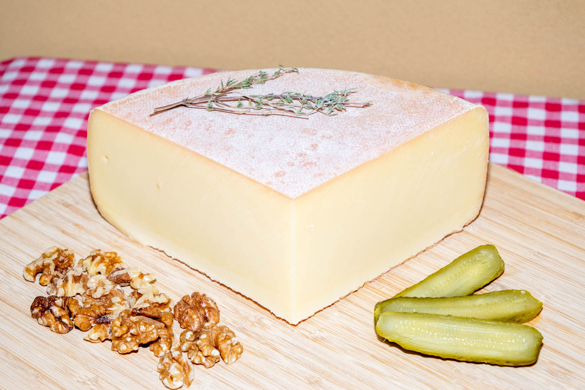 Raclette suisse de montagne, demi-meule avec noix et cornichons